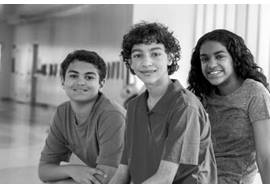 Two Teen Boys and One Teen Girl Sitting in Hallway 