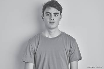 Male teen standing against a blank wall