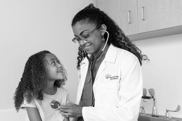 Dr. Delerme and listening to patient's heart in exam room