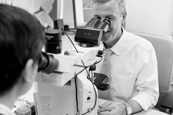 A male pathologist looking into a microscope